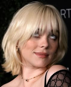 a woman with blonde hair and blue eyes wearing a black dress is looking at the camera