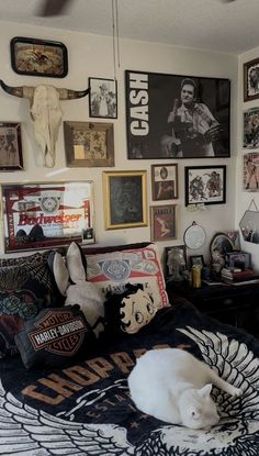 a bedroom with many pictures on the wall and a white cat laying on it's bed