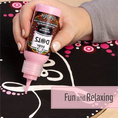 a person is painting with pink paint on a black and white tablecloth that says fun and relaxing