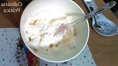 a white bowl filled with ice cream next to two spoons on top of a table