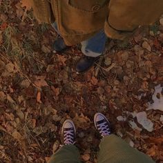 two people standing in the leaves with their shoes on