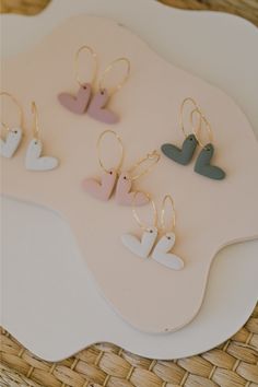 small earrings are displayed on a white tray with pink and blue shapes in the shape of hearts