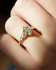 a woman's hand with a ring on it that has a diamond in the middle