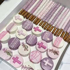 a box filled with pink and white decorated cookies on top of a table next to crackers