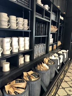 many cups and mugs are lined up on the shelves next to eachother