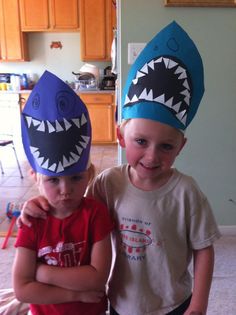 two young boys wearing hats with shark teeth on their heads, standing next to each other