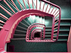 a pink spiral staircase with green walls and carpet