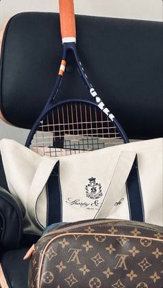 a tennis racket and bag sitting on top of a chair next to a purse