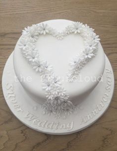 a white heart shaped cake with flowers on it's sides and the words love is in the middle