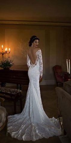 a woman in a wedding dress standing next to a couch with candles on the wall