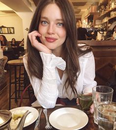 a woman sitting at a table with plates of food and drinks in front of her