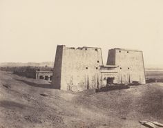 an old photo of two brick buildings in the middle of a desert area with no people around