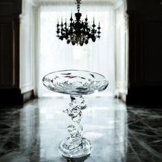 a glass bowl sitting on top of a marble floor next to a chandelier