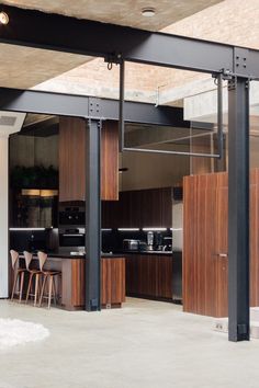 an open kitchen and dining area with wood accents on the walls, along with black steel barstools