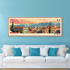 a painting hanging on the wall above a white couch in a room with blue walls