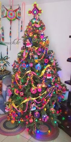 a brightly colored christmas tree in a living room with decorations on the wall and floor