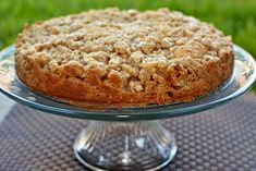 a close up of a cake on a glass platter with grass in the background