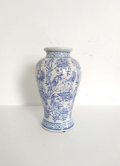 a blue and white vase sitting on top of a table next to a wall in the background