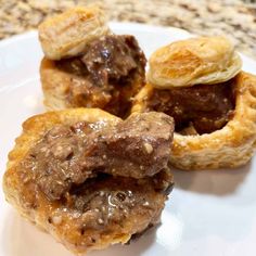 three pastries on a white plate with chocolate sauce and pastry toppings in the middle