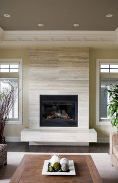 a living room filled with furniture and a fire place in front of two windows on either side of the fireplace