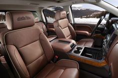 the interior of a vehicle with brown leather seats and snow covered mountains in the background