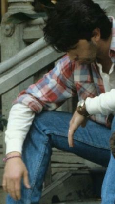 a man sitting on the steps with a small cat in his lap and looking down at him