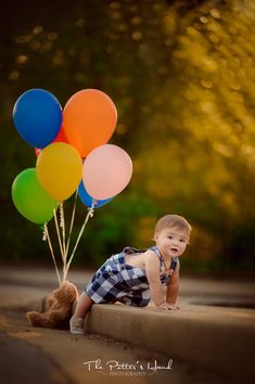 a little boy is sitting on the ground with balloons