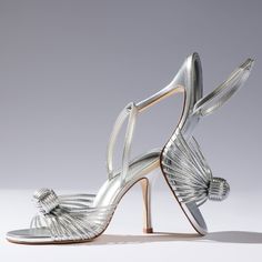 a pair of silver high heeled shoes with bows