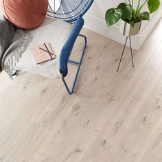 a blue chair sitting on top of a wooden floor next to a potted plant