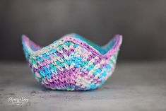 a small knitted bowl sitting on top of a table next to a gray wall