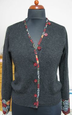 a mannequin wearing a gray cardigan with red and black buttons on it