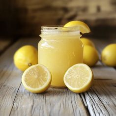 a mason jar filled with lemonade sitting on top of a wooden table next to sliced lemons