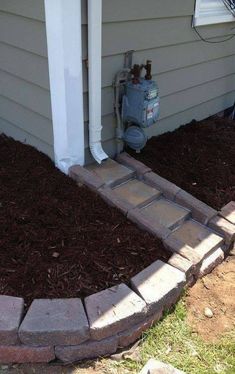 a fire hydrant in front of a house with mulch on the ground next to it