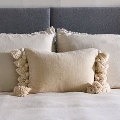 a bed with white pillows and two pom - poms on the pillowcase