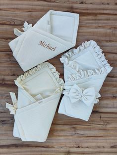 three white towels with ruffles and the word michael written on them are sitting on a wooden surface