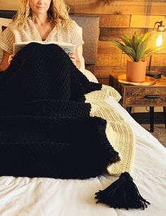 a woman sitting on top of a bed next to a pile of knitted blankets