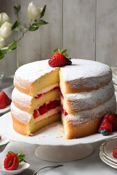 a cake with two slices cut out and covered in powdered sugar next to strawberries