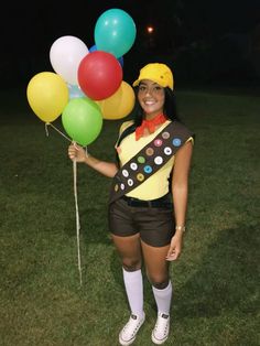 a woman is holding some balloons in her hand and posing for the camera at night