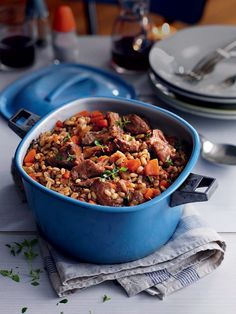 a blue casserole dish filled with meat and veggies on a table