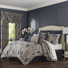 a bedroom with blue walls and wooden flooring has a large bed covered in an intricately designed comforter