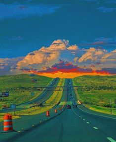 the sun is setting on an empty highway with traffic cones in the foreground and clouds in the background