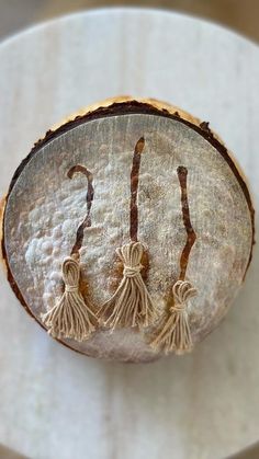 three tasseled earrings on a piece of wood sitting on top of a table