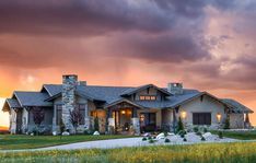 a large house sitting on top of a lush green field under a cloudy sky at sunset