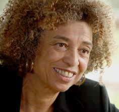 a close up of a person wearing a suit and smiling at the camera with curly hair