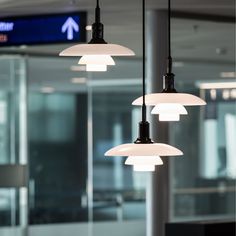 three lights hanging from the ceiling in an airport lobby with glass walls and windows behind them