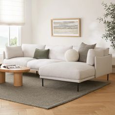 a white couch sitting on top of a wooden floor in a living room next to a window