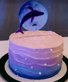 there is a cake with a dolphin on it and the moon in the sky behind it