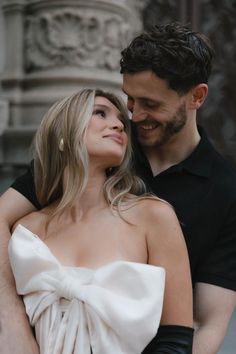 a man standing next to a woman wearing a white dress and black gloves on her chest