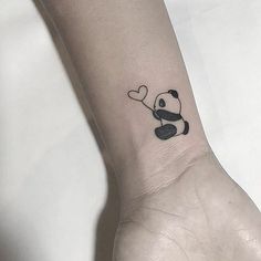 a small panda bear holding a heart shaped balloon tattoo on the left inner forearm and wrist