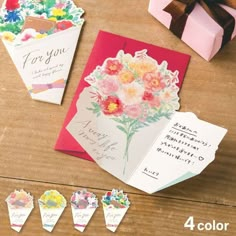 some cards are sitting on a table next to a box and two boxes with flowers in them